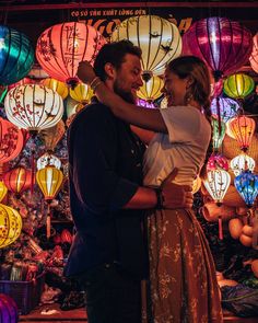 a man and woman embracing in front of colorful lanterns