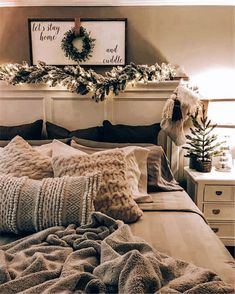 a bed topped with lots of pillows next to a christmas wreath on top of a wall