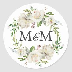 a white flower wreath with the letter m and m on it's side round sticker