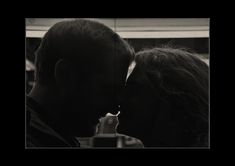 a man and woman kissing each other in black and white