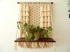 a potted plant sitting on top of a wooden shelf next to a wall hanging