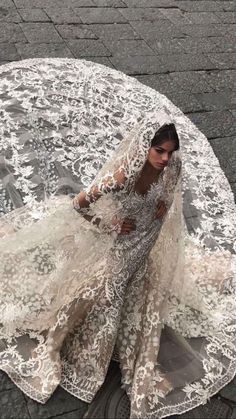 a woman in a wedding dress is sitting on the ground with her veil over her head