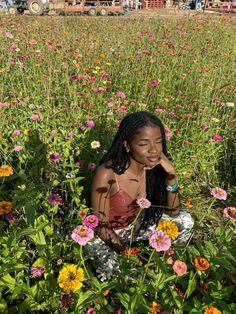 a woman sitting in the middle of a field full of wildflowers and other flowers