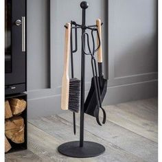 a coat rack with three umbrellas and two brooms on it in front of a fireplace