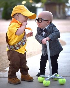 two young boys dressed up as babies on skateboards and one is playing with a scooter