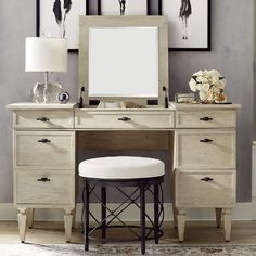 a desk with a mirror, stool and pictures on the wall in front of it