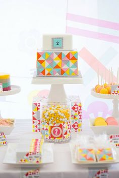 a table topped with lots of colorful desserts and candies on top of plates