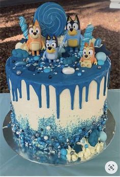 a blue and white frosted cake with cartoon characters on the icing drips