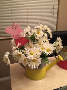 a watering can filled with daisies and pep the pig