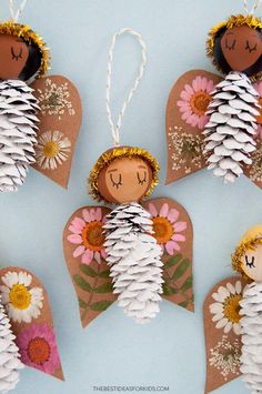 three paper angel ornaments with pine cones and flowers in the shape of angels on them