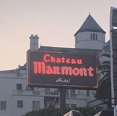 a sign for chateau marmontt hotel in front of a large white building with a clock tower