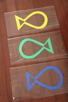 four different colored fish stickers on a wooden floor