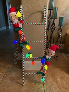 two elfs are hanging on a christmas tree with candy canes in the shape of santa's helpers