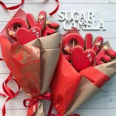 some cookies are wrapped in red paper and tied together with ribbons on a white table