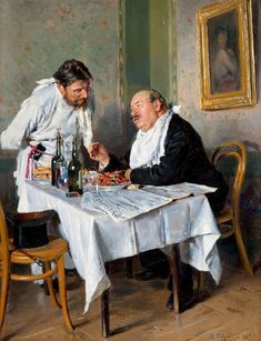 two men sitting at a table with wine and food in front of them, talking