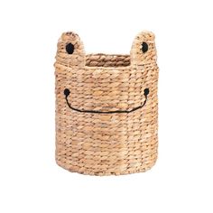 a woven basket with a smiling face on the front and sides, it has black handles