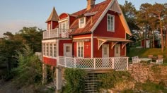 a red house sitting on top of a lush green hillside