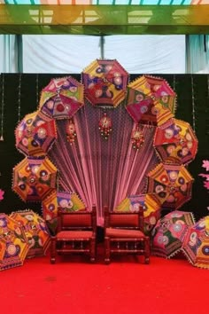 an elaborately decorated stage with chairs and umbrellas on the red carpeted floor