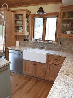 a kitchen with granite counter tops and wooden cabinets, stainless steel dishwasher in the center