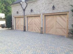 a brick driveway with three wooden garage doors