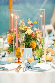 the table is set with flowers, candles and wine glasses for an elegant wedding reception