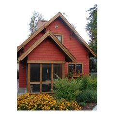 an image of a red house with yellow flowers in the front yard and landscaping around it