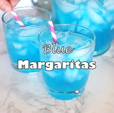 three glasses filled with blue margaritas on top of a table