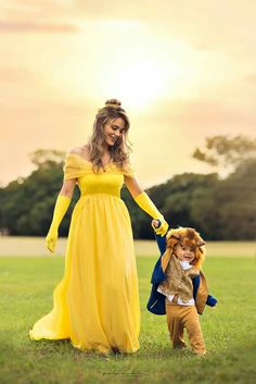 a woman in a yellow dress holding the hand of a little boy dressed as beast