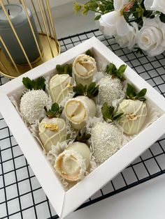 a box filled with chocolate covered strawberries on top of a tiled floor next to flowers