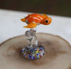 an orange and white fish figurine sitting on top of a piece of wood