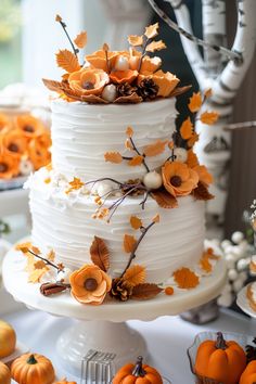 a three tiered white cake with orange flowers and leaves on the top is surrounded by other desserts