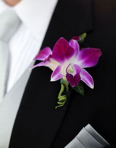 a man in a tuxedo is wearing a boutonniere with purple flowers on it