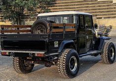 an old black truck parked in front of a large building with steps on the side