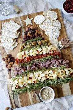 a wooden cutting board topped with cheese and meats next to crackers on top of a table