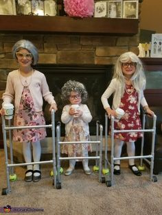 three dolls are standing next to each other in front of a fire place with an iron fence