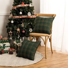 a christmas tree with presents under it in front of a chair and other holiday decorations