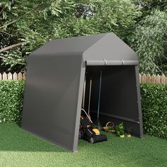 an outdoor storage shed with the door open and lawn mowers in front of it