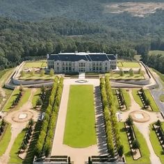 an aerial view of a large white house surrounded by lush green fields and trees in the background