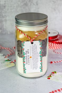 a jar filled with cookies and candy canes on top of a table next to twine of twine