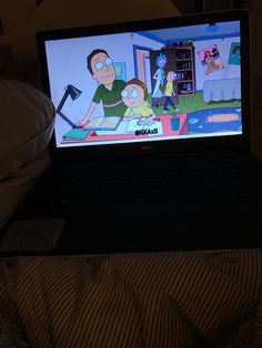 an open laptop computer sitting on top of a bed next to a cartoon wallpaper