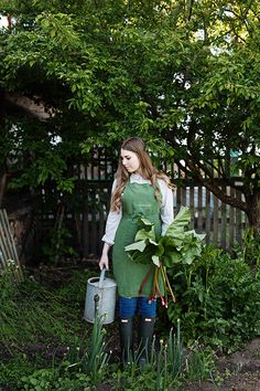 a woman in an apron holding a watering can