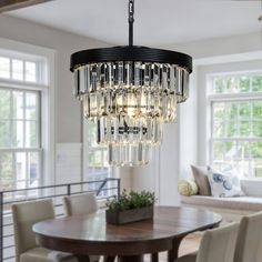 a chandelier hanging from the ceiling in a dining room with chairs and table