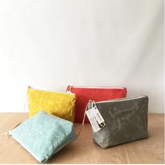 three different colored pouch bags sitting on top of a wooden table next to each other