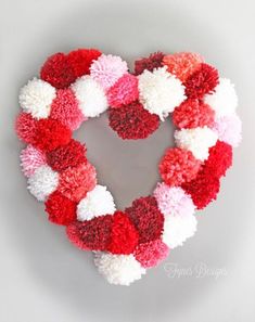 a heart shaped wreath made with pom - poms