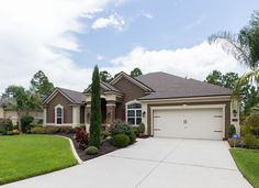 a large house with lots of trees and bushes in front of the garage door is shown