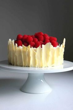 a cake with white frosting and raspberries on top