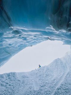 two people are skiing in the snow near an ice cave