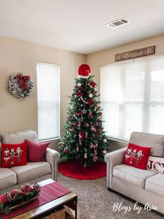 a living room decorated for christmas with red and white decorations on the tree, couches and coffee table