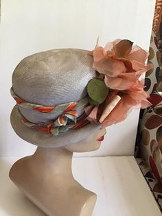 "Vintage 1950's 1960's light Gray Straw hat with Dark Peach flowers. The label is *Grayce Hats*. Does have condition issues and will be sold as is. (SEE PIX). *MORE INFORMATION BELOW* CONDITION: Has discoloration around the inside brim in the front on the straw and on the band/ribbon (SEE PIX). On the inside band on the right side there is a small dark spot. In the back of the hat on the brim area there is some wear. This appears to be from where the hatpin was always used (SEE PIX). Sold As Is! 1960s Hats, Vintage Clothing Boutique, Pillbox Hat, Peach Flowers, Pill Boxes, Straw Hat, Vintage 1950s, Light Gray, The Label