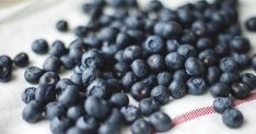 some blueberries are laying on top of a white table cloth with red and black stripes